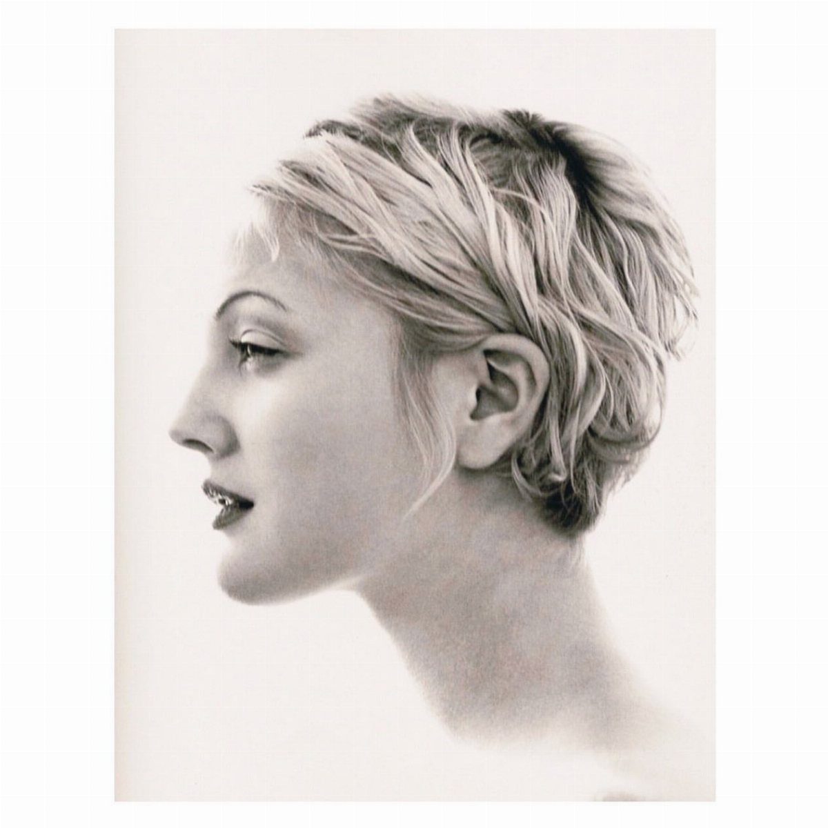 A woman in profile showcasing a short, textured pixie cut with layered blonde hair.